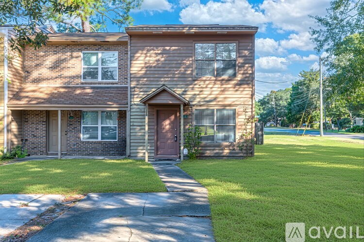 A two-story brick house with a brown door and windows.