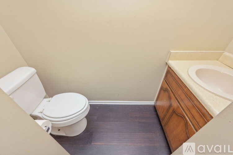 A white toilet sits next to a bathtub in a small bathroom.