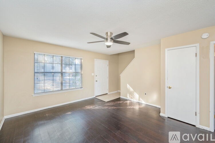 A room with a ceiling fan and a window with blinds.