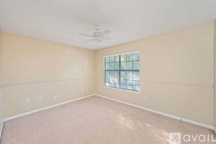 A room with a ceiling fan and a window with blinds.