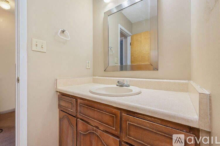 A bathroom with a sink, mirror, and wooden cabinet.