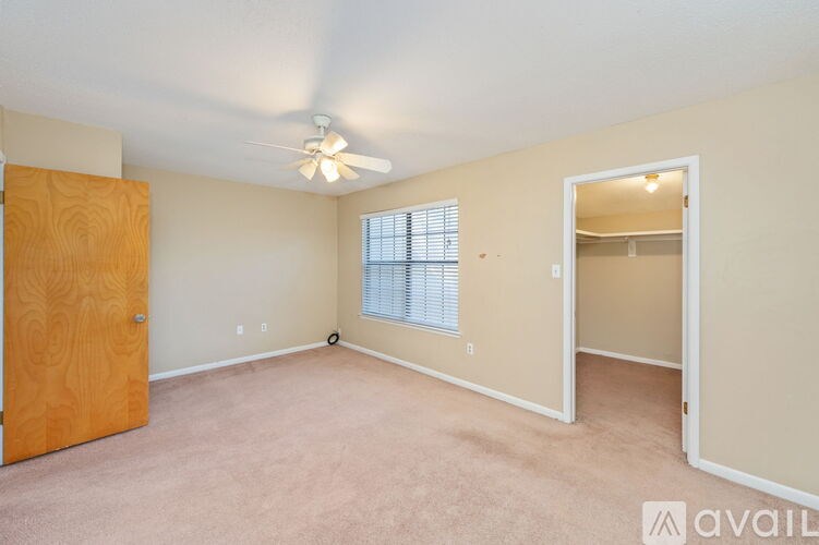A room with a ceiling fan and a window with blinds.