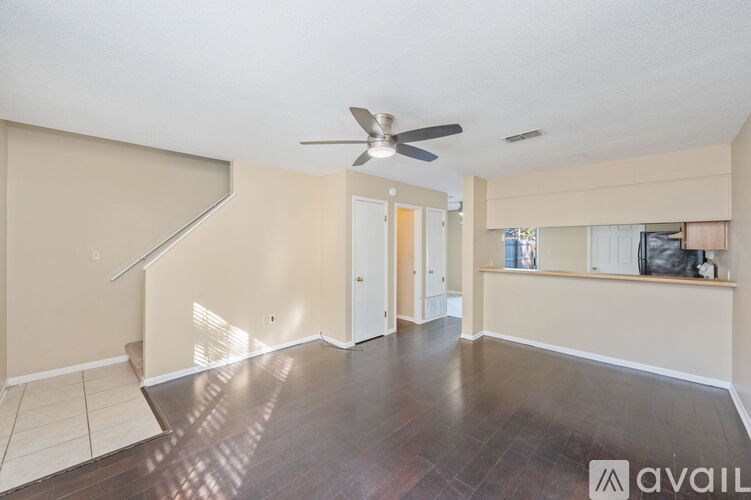 A spacious room with a fan and wooden flooring.