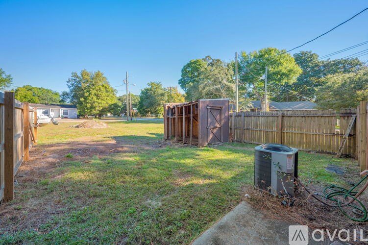 A backyard with a fence, a shed, and a utility box.