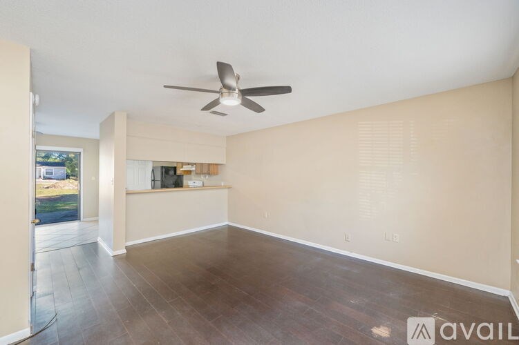 A spacious room with a ceiling fan and wooden flooring.