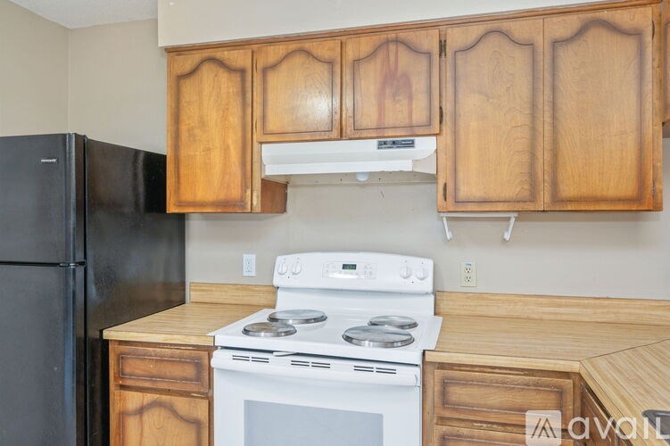 A kitchen with wooden cabinets and a black refrigerator.
