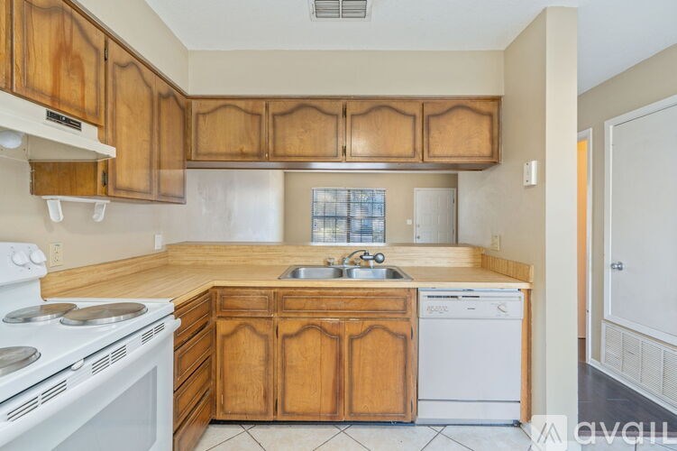 A kitchen with wooden cabinets and a white stove top oven.