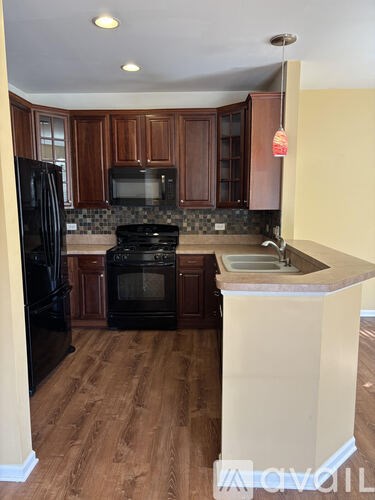 A kitchen with black appliances and wooden cabinets.