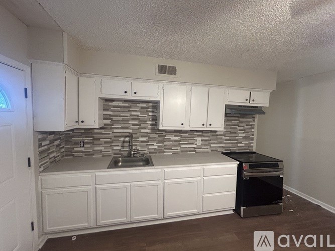 A kitchen with white cabinets and a stone backsplash.
