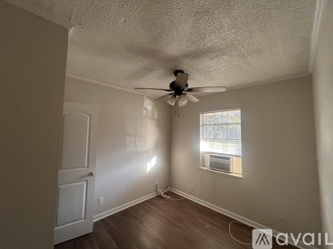 A room with a ceiling fan and a window letting in sunlight.