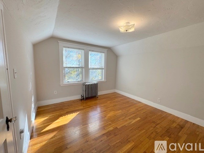 A room with wooden floors and a window with a radiator beneath it.