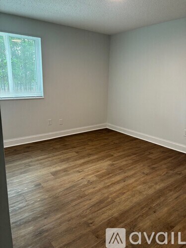 A room with wooden flooring and a window with blinds.