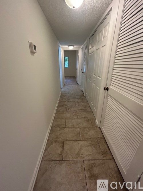 A long hallway with white walls and a tiled floor.