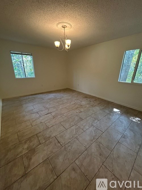 A room with tiled flooring and two windows.