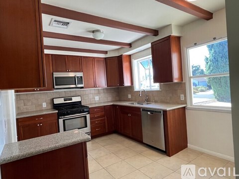 A kitchen with brown cabinets and a granite counter.