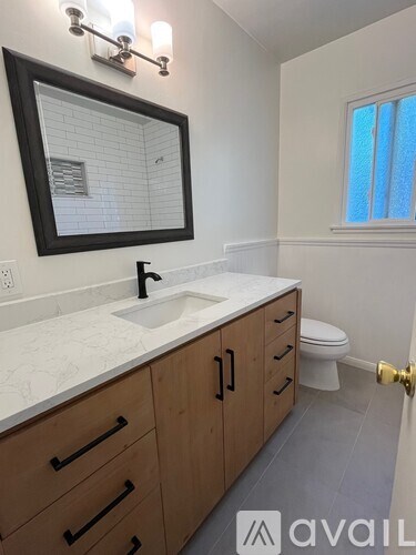 A bathroom with a sink, mirror, and toilet.