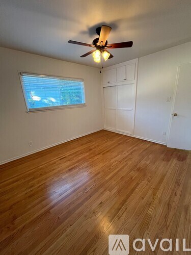A room with wooden flooring and a ceiling fan.