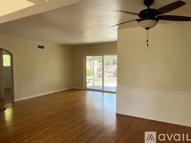 A room with a ceiling fan and wooden flooring.