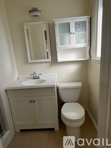 A white bathroom with a toilet, sink and medicine cabinet.