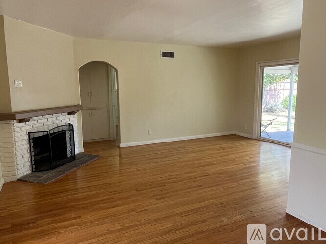 A living room with a fireplace and wood flooring.
