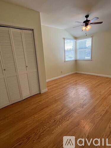 A room with a ceiling fan and wooden flooring.
