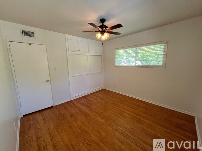A room with wooden flooring and a ceiling fan.