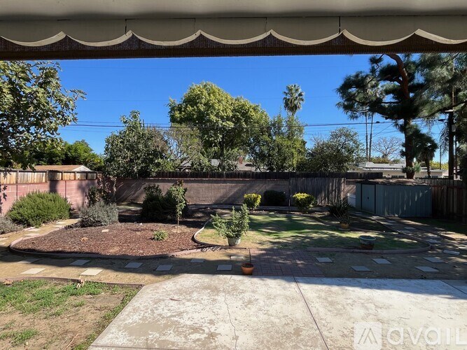 A backyard with a circular garden and a concrete patio.