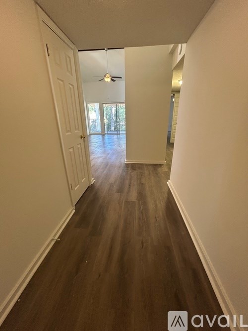 A long hallway with wood floors and white walls.