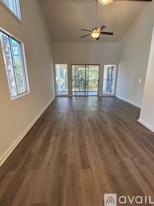 A spacious room with wooden flooring and a ceiling fan.