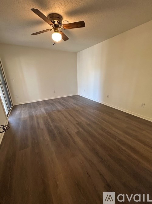 A room with a ceiling fan and wooden flooring.