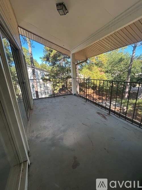A balcony with a black railing and a view of trees and a building.