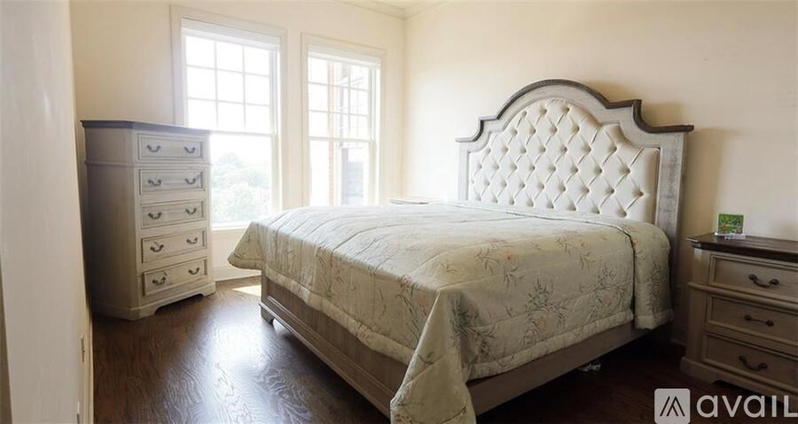 A bedroom with a large bed, a chest of drawers, and a window.
