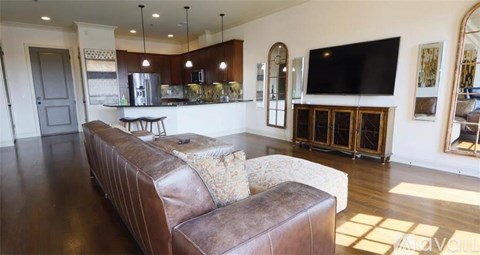 A brown leather couch sits in a living room with a bar area in the background.