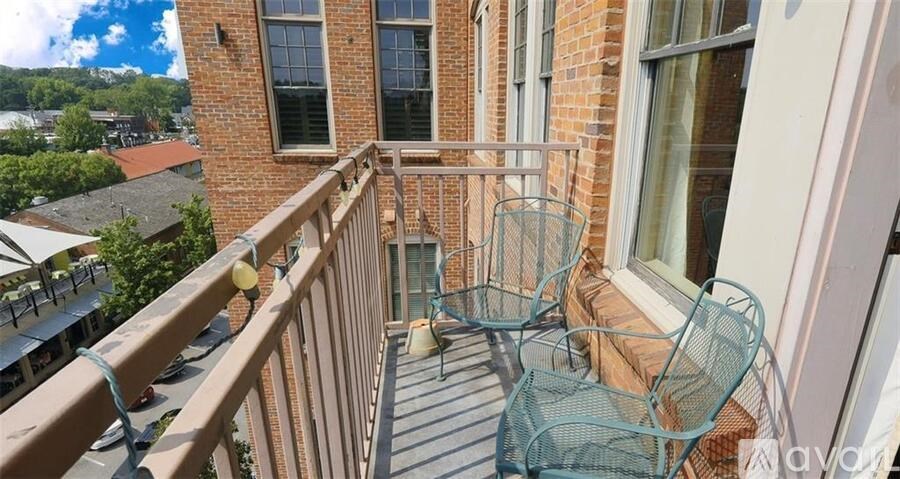 A balcony with a table and chairs overlooking a cityscape.