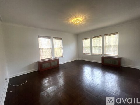 A room with wooden floors and three windows.