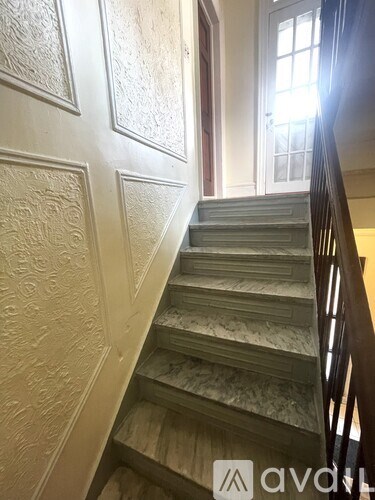 A staircase with a wooden handrail and a wall with carved designs.