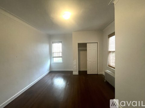 A room with wooden floors and white walls, with a window and a door visible.