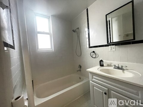 A bathroom with a white tub, sink, and toilet paper roll.