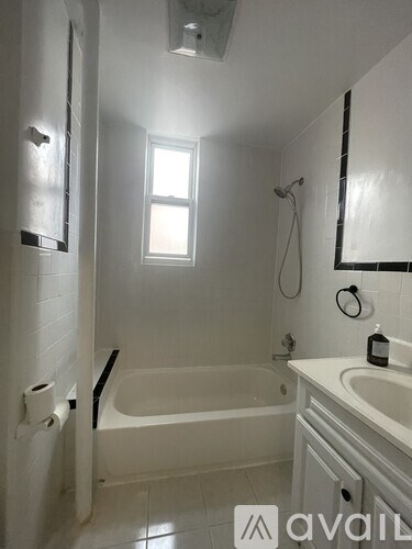 A white bathroom with a tub, sink, and toilet paper.