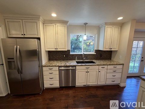 A kitchen with white cabinets and a granite countertop.