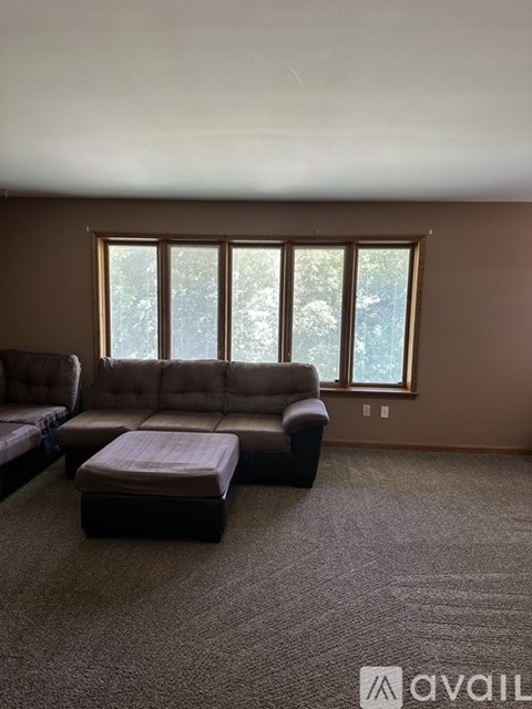 A living room with a brown couch and ottoman.