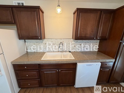 A kitchen with brown cabinets and a white dishwasher.