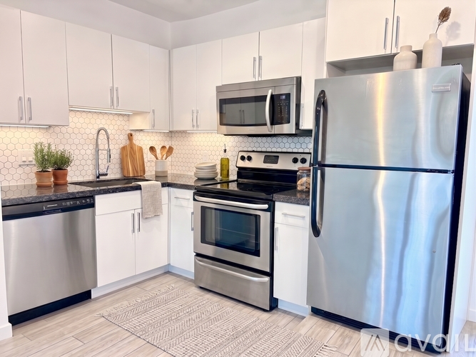 A kitchen with a stainless steel refrigerator, microwave, and a wooden table with two chairs.