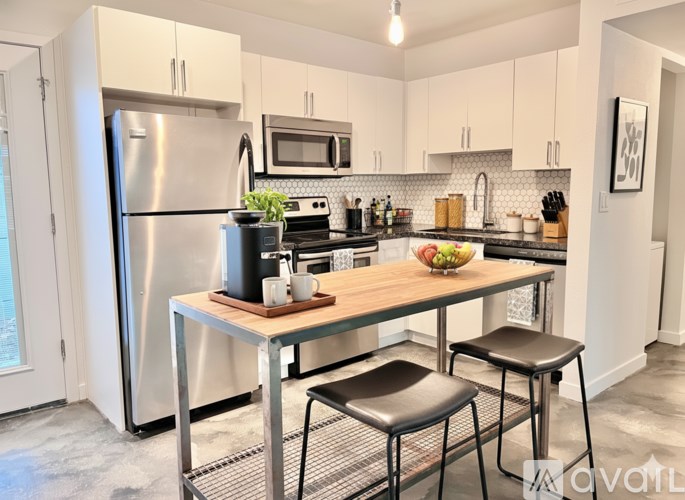 A kitchen with a stainless steel refrigerator, microwave, and a wooden table with two chairs.