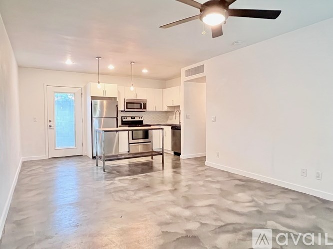 A spacious kitchen with a central island and a ceiling fan.