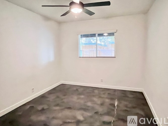 A room with a ceiling fan and a window with blinds.