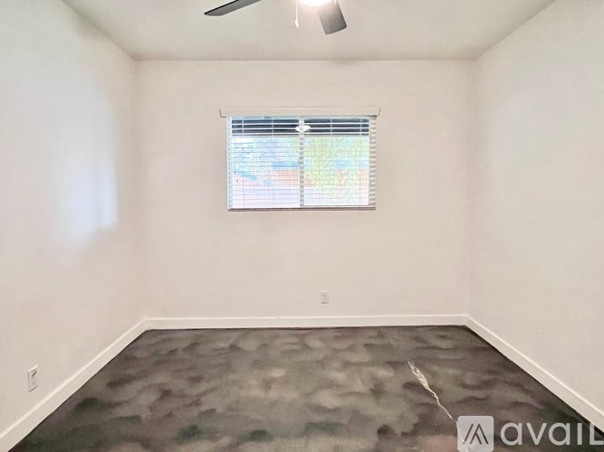 A room with a ceiling fan and a window with blinds.