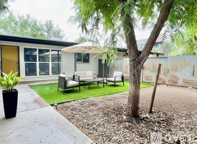 A patio area with a tree, chairs, and a table.
