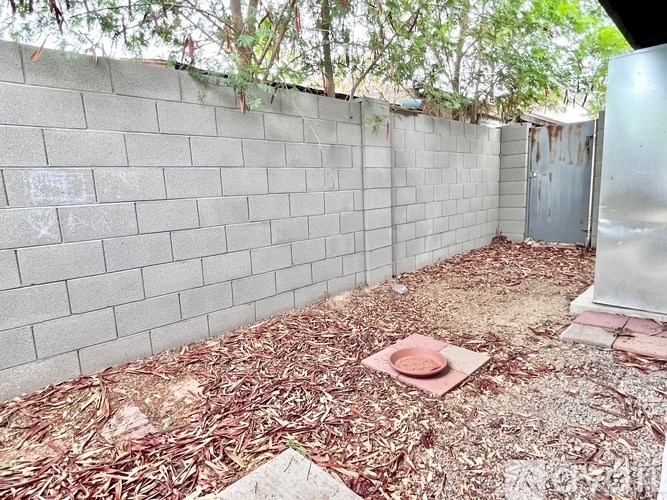 A backyard with a wall, a door, and a mat on the ground.