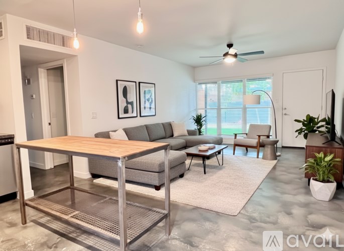 A living room with a grey couch, a wooden table, and a ceiling fan.